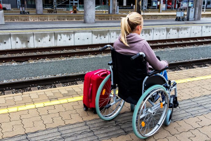 イギリスの鉄道駅で電車を待つ車椅子女性