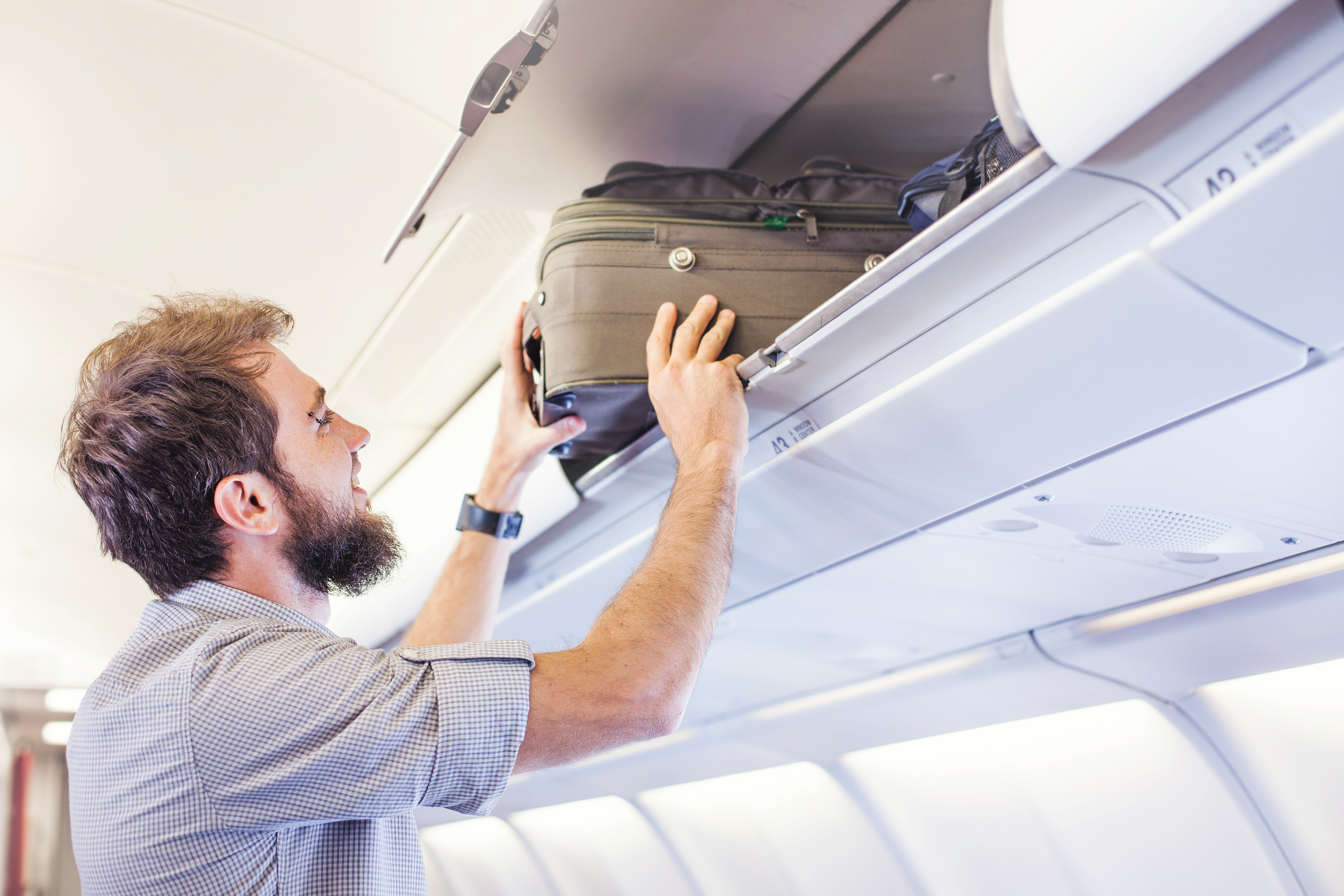 機内で荷物を収納する男性